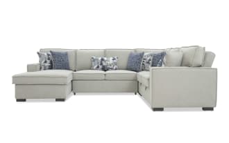 Light gray fabric sectional sofa with chaise lounge, featuring plush cushions and blue patterned throw pillows, modern style seating.