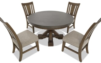 Dining set with round dark wood table and four wooden chairs featuring beige upholstered seats and nailhead trim, rustic style.
