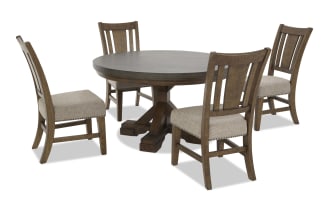 Dining set with round dark wood table and four wooden chairs featuring beige upholstered seats and nailhead trim, rustic style.