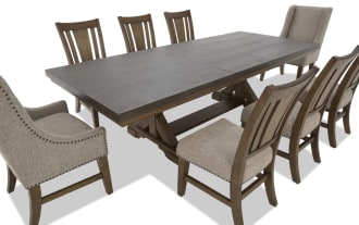 Rectangular dark wood dining table set with eight chairs, featuring beige upholstered seats and backs, nailhead trim, and a mix of high-back armchairs and side chairs.