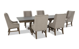 Rectangular dark wood dining table with six beige upholstered high-back chairs featuring nailhead trim and wooden legs, modern farmhouse style.