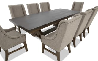 Rectangular dark wood dining table with eight beige upholstered high-back chairs featuring nailhead trim and wooden legs, modern style.