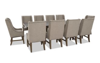 Dining set with a rectangular dark wood table and ten beige upholstered chairs featuring nailhead trim and wooden legs, suitable for large gatherings.