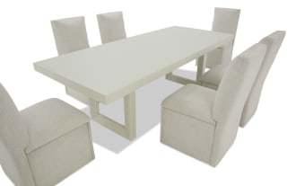 Modern dining set with six beige upholstered chairs and a rectangular light gray table, featuring a minimalist and contemporary design.