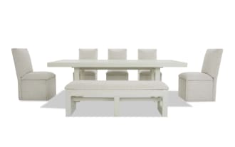 Modern dining set with a rectangular white wooden table, six beige upholstered chairs, and a matching cushioned bench, ideal for contemporary interiors.