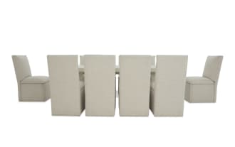 Beige upholstered dining chairs with high backs arranged around a rectangular white dining table, showcasing modern fabric seating for eight.