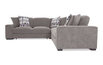 Gray fabric sectional sofa with tufted armrests, plush cushions, and geometric patterned throw pillows, ideal for modern living rooms.