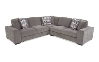 Gray fabric sectional sofa with tufted armrests, plush cushions, and geometric patterned throw pillows, ideal for modern living rooms.