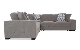 Gray fabric sectional sofa with tufted armrests, plush cushions, and geometric patterned throw pillows, designed for modern living rooms.