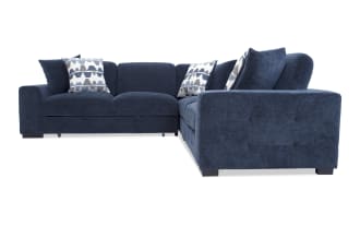 Navy blue fabric sectional sofa with plush cushions, tufted armrests, and three patterned throw pillows, designed for modern living rooms.