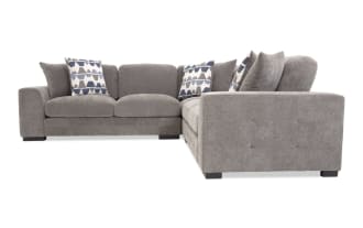 Gray fabric sectional sofa with tufted armrests, plush cushions, and three patterned blue and white throw pillows, ideal for modern living rooms.