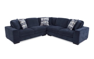 Dark blue velvet sectional sofa with tufted armrests, thick cushions, and three patterned accent pillows, ideal for modern living rooms.
