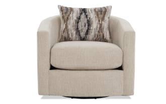 Beige textured fabric swivel armchair with rounded arms and a patterned brown, beige, and black accent pillow for modern living room seating.