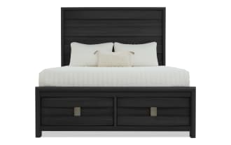 King-size bed with black wood frame, horizontal panel headboard, and two storage drawers at the footboard, styled with white bedding and pillows.