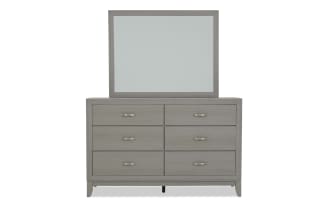 Gray wooden dresser with six drawers and brushed metal handles, topped with a matching framed mirror, modern bedroom furniture design.