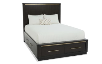 Dark wood platform bed with tall headboard and brass accents, featuring white bedding and two storage drawers at the base.