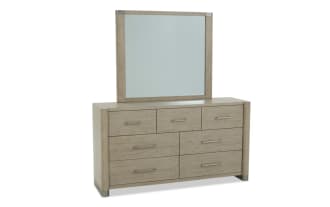 Modern wooden dresser with six drawers and three smaller top drawers, featuring a matching rectangular mirror with a light wood finish and metal handles.