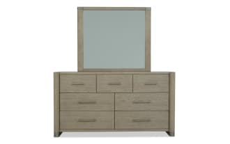 Modern wooden dresser with six drawers and three smaller top drawers, featuring a matching rectangular mirror with a light wood finish and metal handles.