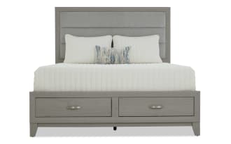 Gray wooden bed frame with a padded headboard and two under-bed storage drawers, styled with white bedding and decorative pillows.