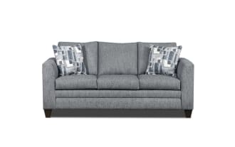 Gray fabric three-seater sofa with dark wooden legs and two patterned blue and white throw pillows, modern living room furniture.
