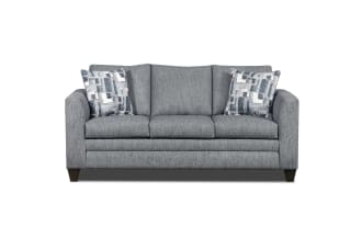 Gray fabric three-seater sofa with dark wooden legs and two patterned blue and white throw pillows, modern living room furniture.