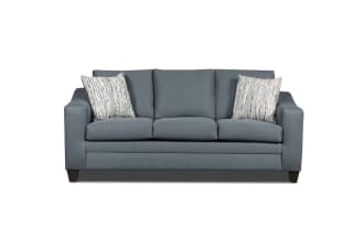 Modern blue fabric sofa with three seat cushions, two patterned throw pillows, and dark wooden legs, ideal for living room seating.