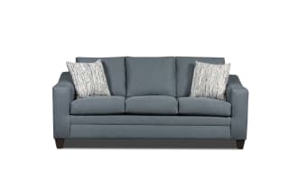 Modern blue fabric sofa with three seat cushions, two patterned throw pillows, and dark wooden legs, ideal for living room seating.
