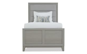 Gray wood bedroom set with upholstered headboard bed, matching dresser with mirror, and nightstand with table lamp, modern style