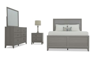 Modern gray wooden bedroom set with upholstered headboard, includes king bed, two-drawer nightstand with lamp, and six-drawer dresser with mirror.