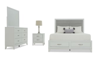White bedroom furniture set including a queen bed with gray upholstered headboard and storage drawers, white nightstand with lamp, and matching dresser with mirror.