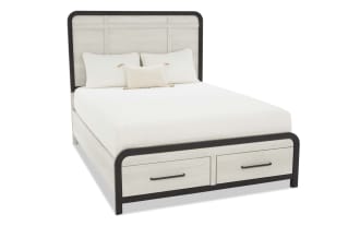 King-size bed with light wood panel headboard and footboard, black metal frame, two storage drawers, and white bedding with pillows.