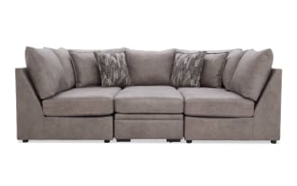 Modern gray fabric sectional sofa with plush cushions and patterned throw pillows, featuring a sleek, contemporary design for living room seating.