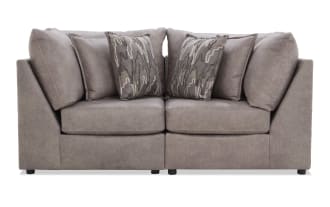 Modern gray fabric sectional sofa with plush cushions and patterned throw pillows, featuring a sleek, contemporary design ideal for living rooms.