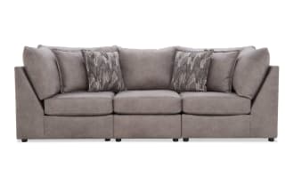 Modern gray fabric sofa with plush cushions and patterned accent pillows, featuring a clean, boxy design and low black legs.