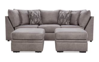 Modern gray fabric sectional sofa with two matching ottomans, plush cushions, and patterned throw pillows, ideal for living room seating.