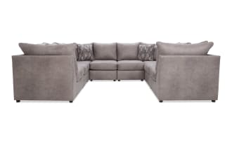 Large U-shaped sectional sofa in soft gray fabric with plush cushions and patterned throw pillows, ideal for spacious living rooms.