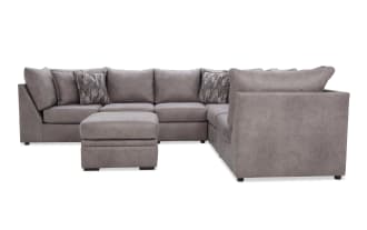 Gray sectional sofa with plush cushions and matching ottoman, featuring a modern design and soft fabric upholstery, ideal for living room seating.