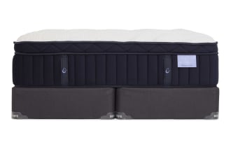 Crescent & Cloud Obsession Plush mattress with quilted white top and navy blue sides, resting on dark gray Bob's foundation base.