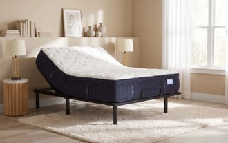 Adjustable bed frame with black metal legs and a dark navy blue mattress featuring a white quilted top, designed for customizable comfort and support.