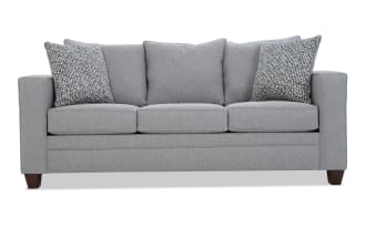 Gray fabric three-seater sofa with square arms, wooden legs, and five cushions including two patterned accent pillows, modern style.