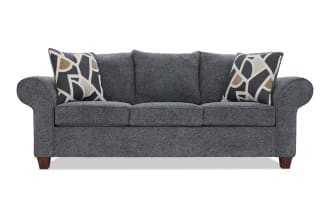 Gray fabric upholstered sofa with rolled arms, three seat cushions, three back cushions, and two decorative geometric pattern throw pillows.