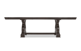 Dark brown wooden dining table with ornate carved pedestal legs and a rectangular top, suitable for formal dining rooms.