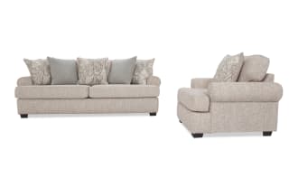 Beige fabric sofa set with rolled arms and dark wooden legs, featuring patterned and solid throw pillows, showcasing a classic, comfortable living room style.