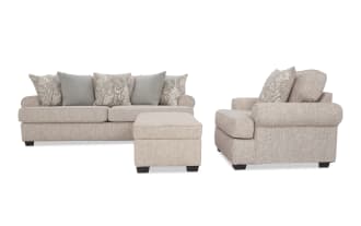 Beige fabric sofa set with rolled arms, dark wooden legs, and patterned throw pillows, paired with a matching ottoman.
