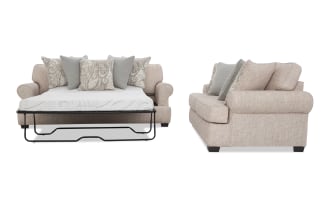 Light beige fabric sofa bed with rolled arms, dark wooden legs, and patterned decorative pillows, shown in open bed position and side view.