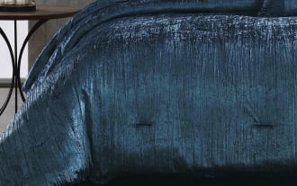 Luxurious navy blue crushed velvet comforter set on a modern bed with matching decorative pillows, featuring a soft, textured fabric and elegant sheen.