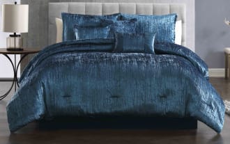Luxurious navy blue crushed velvet comforter set on a modern bed with matching decorative pillows, featuring a soft, textured fabric and elegant sheen.