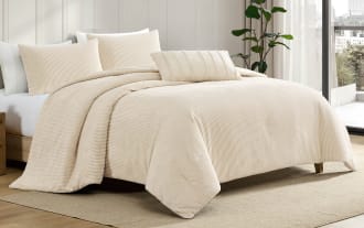 Beige ribbed velvet comforter set with matching pillow shams and decorative pillow on a wooden platform bed in a modern bedroom.