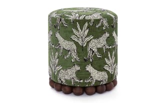 Green cylindrical fabric ottoman with white leopard and leaf patterns, featuring a wooden bead base for stylish living room seating or decor.
