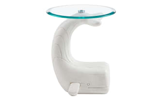 White wooden side table shaped like a whale with a curved tail supporting a round clear glass top, modern nautical decor.
